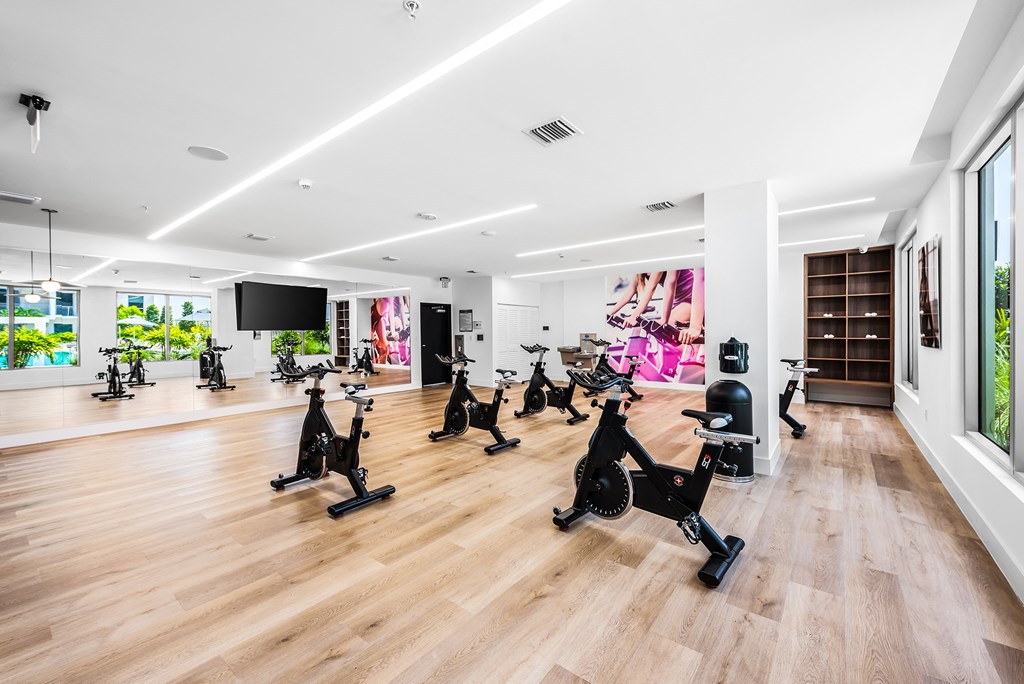 a spacious fitness center with a wood floor and white walls