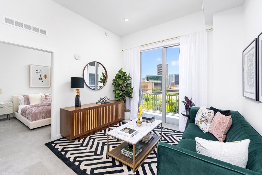 a living room with a green couch and a large window with a view of the city