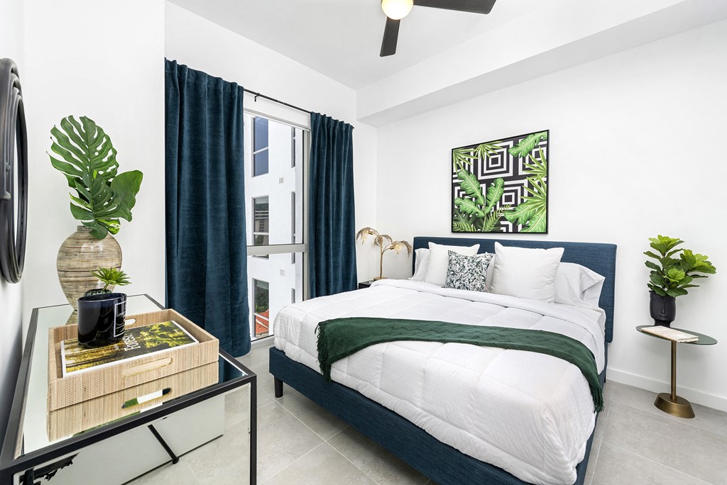 a bedroom with white walls and a white bed with a green blanket