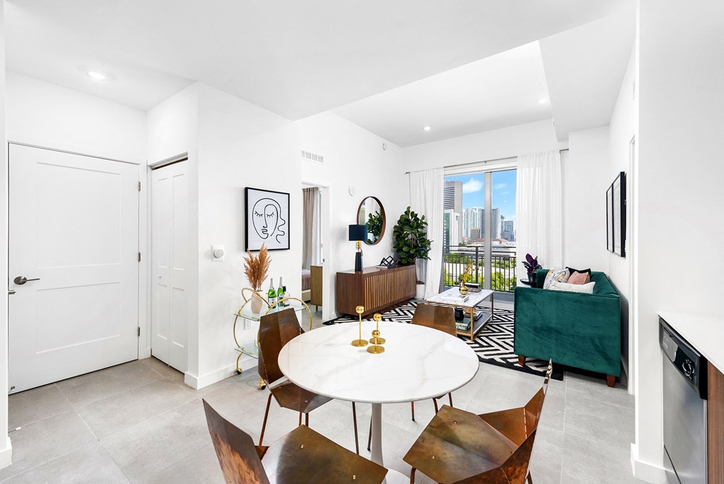 a dining area with a white table and chairs and a large window with a city view
