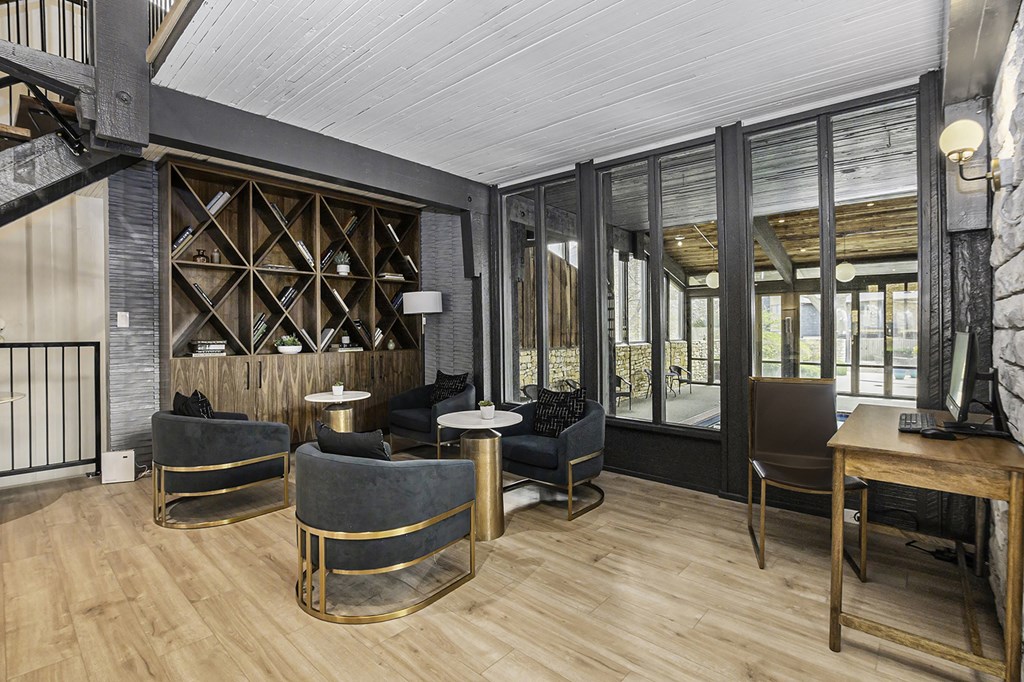 a living room with chairs and a table and a wall of windows