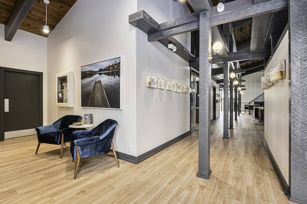 a living room with two chairs and a table and a hallway in the background