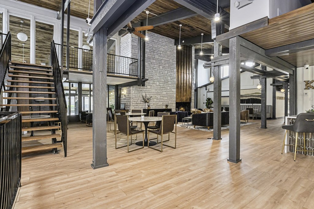 a large lobby with tables and chairs and a staircase
