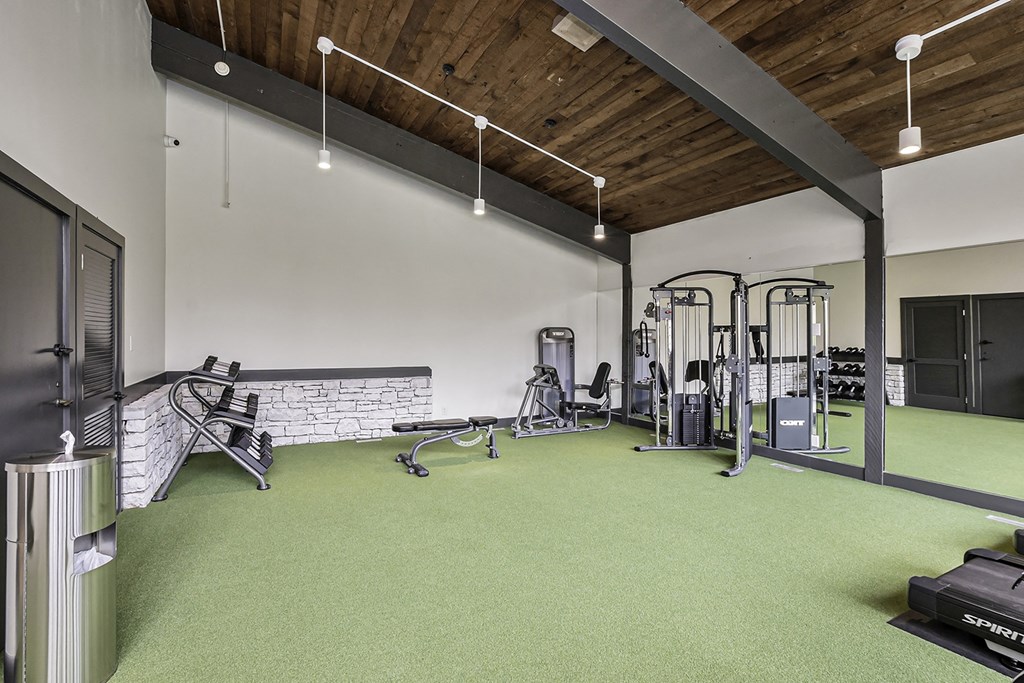 a gym with green carpet and exercise equipment and a brick wall