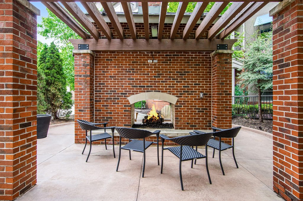 a patio with a table and chairs and a brick fireplace