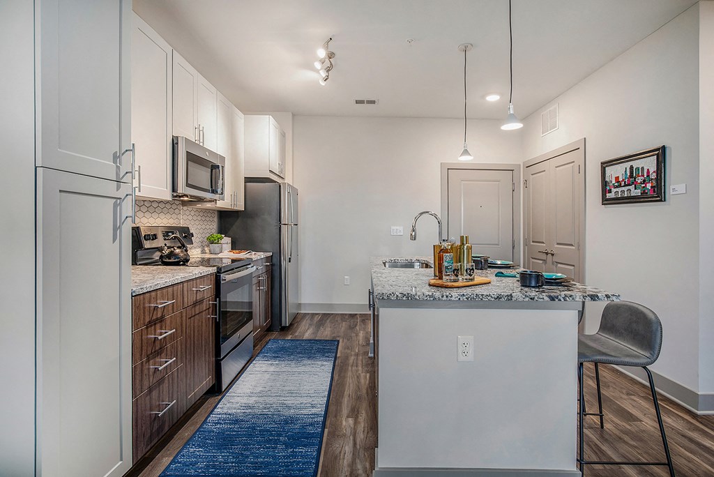 spacious kitchen with stainless steel appliances and granite counter tops at the grove apartments