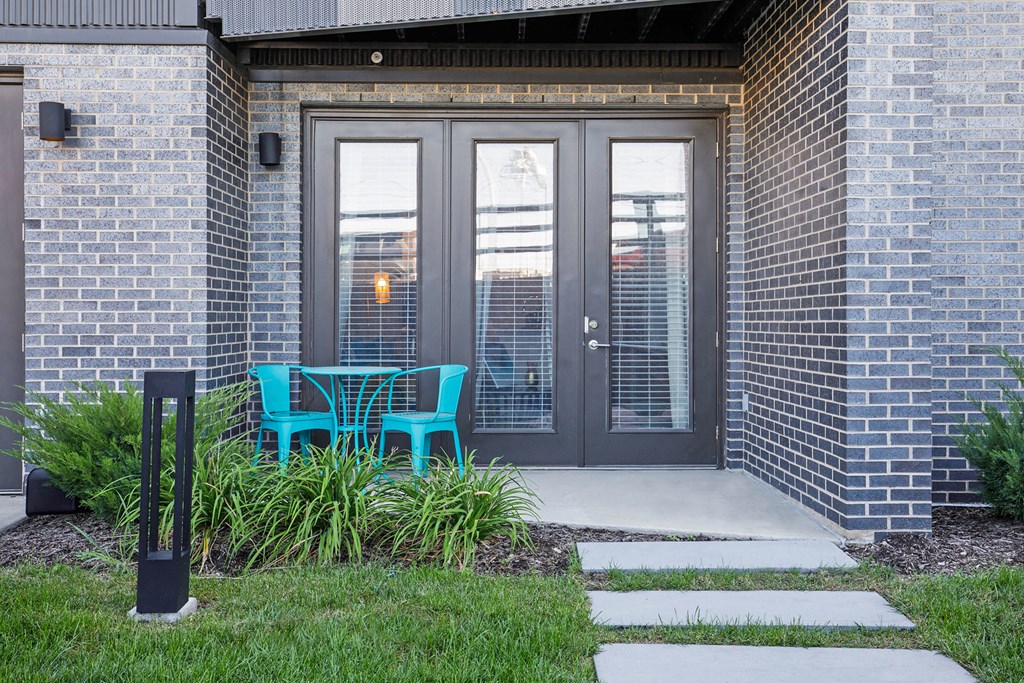 a patio with a blue chair in front of a brick building