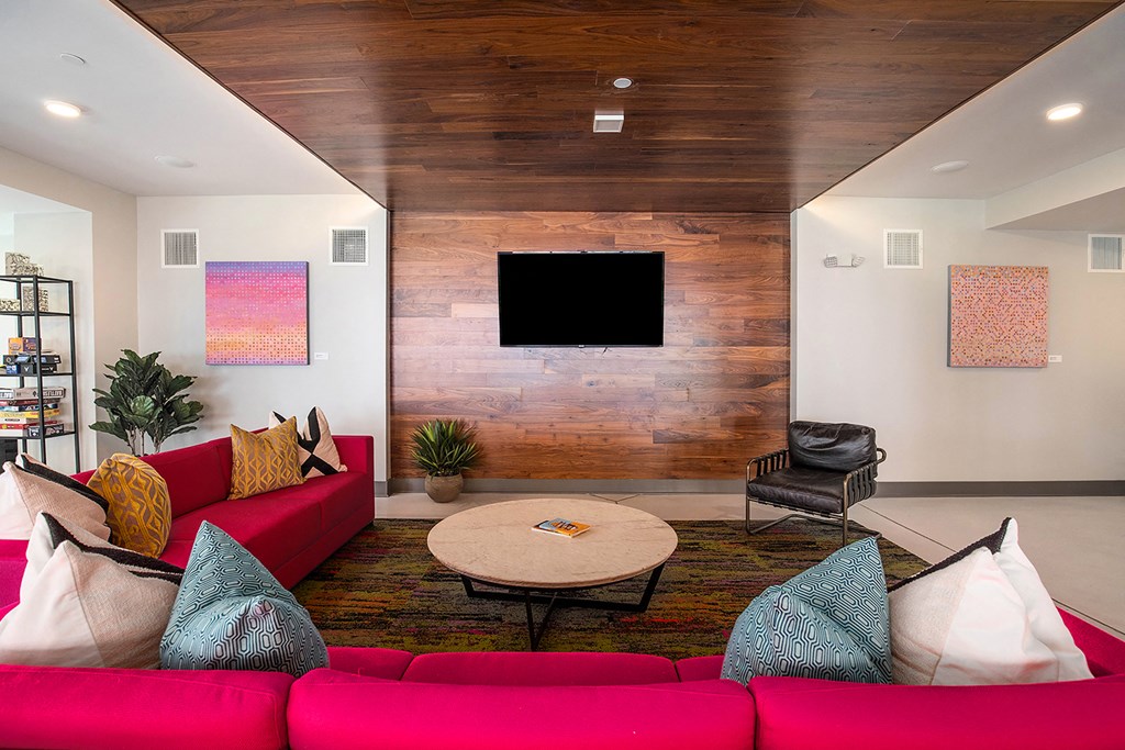 a living room with a red couch and a tv on the wall