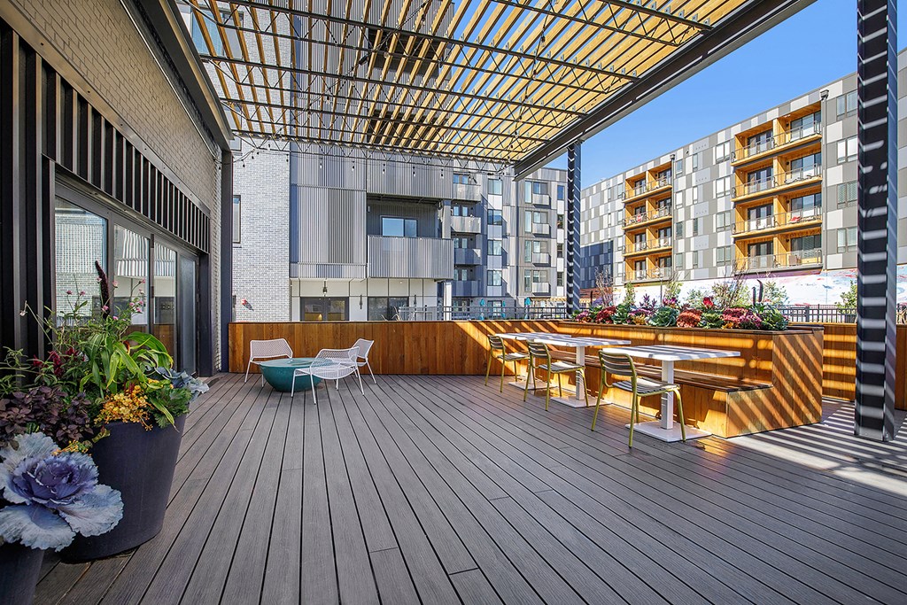 a roof terrace with tables and chairs and a building in the background