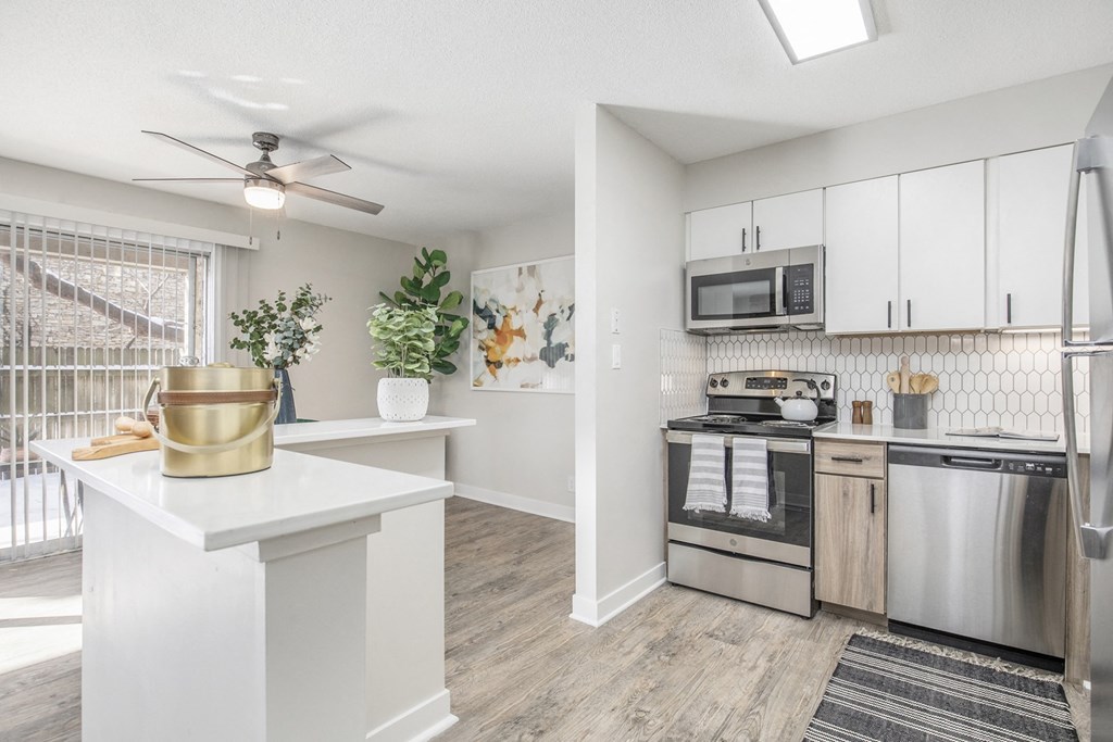 an open kitchen with stainless steel appliances and a ceiling fan