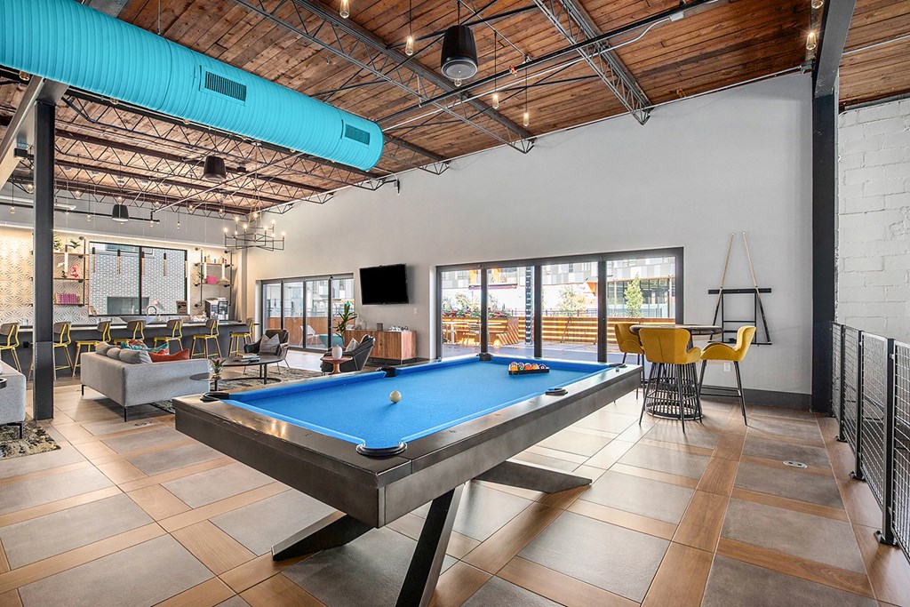 a pool table in a living room with a bar and tables