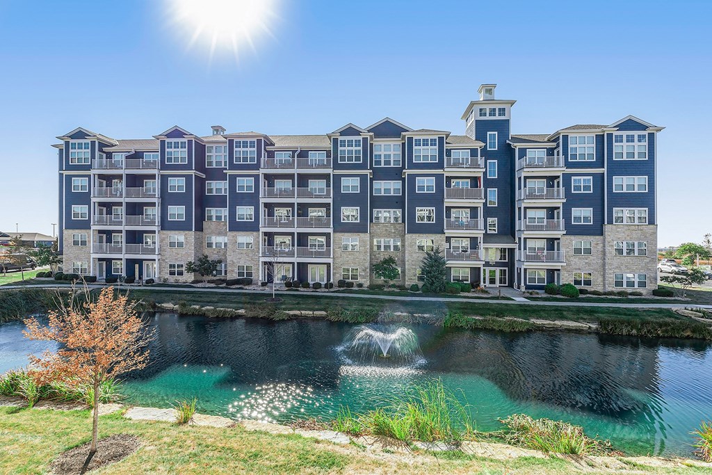 a pond with a fountain in front of an apartment building