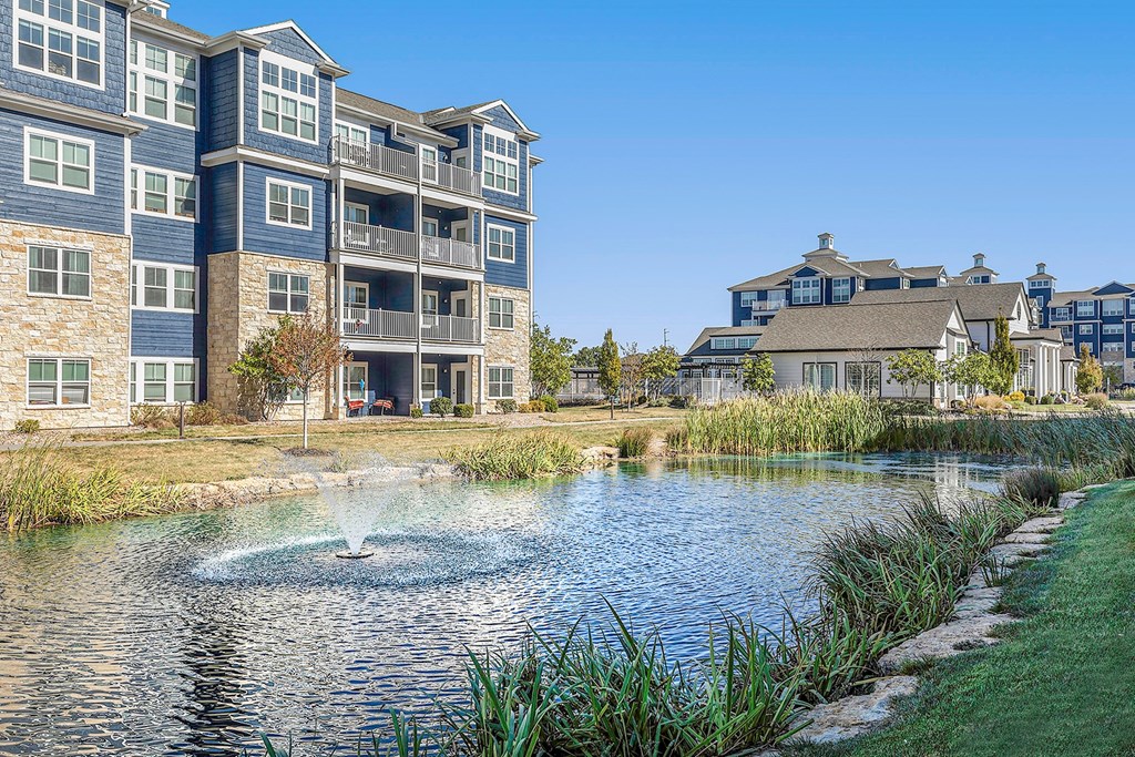 a small pond with a fountain in front of an apartment building