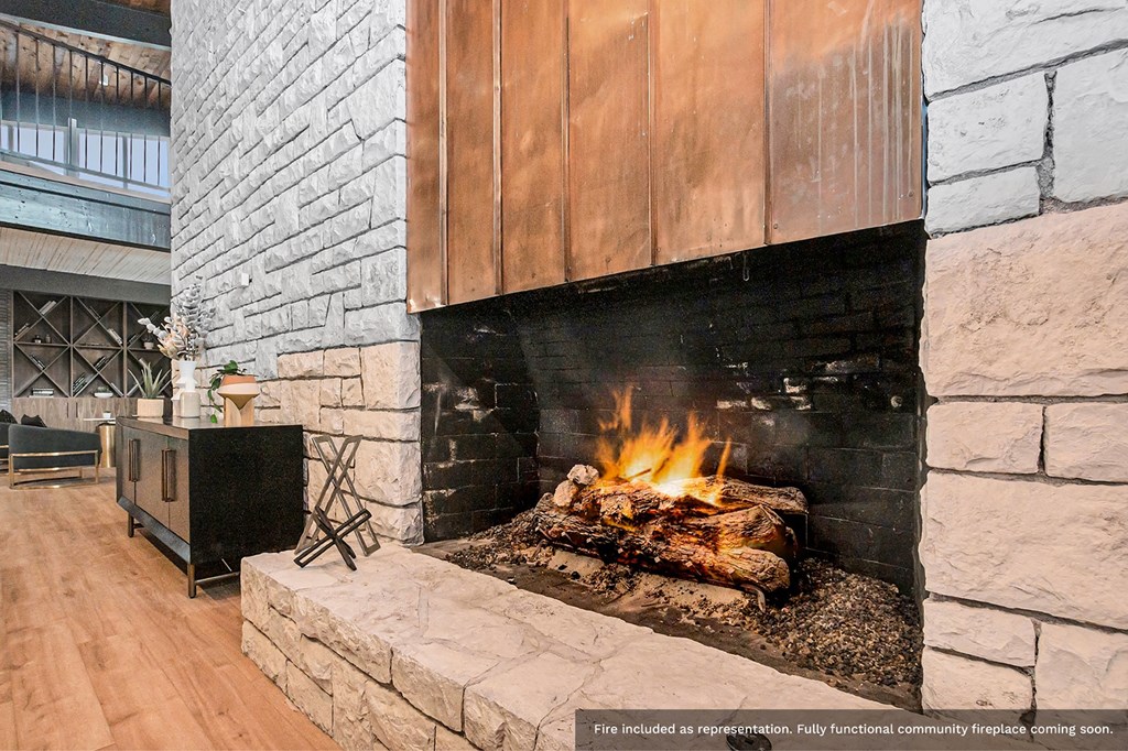 a fireplace in a lobby with a stone wall and a wooden mantle