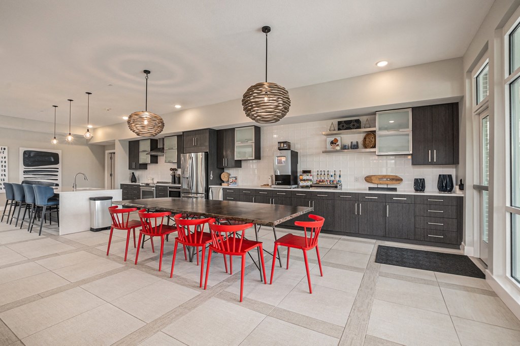a kitchen with a long wooden table and red chairs