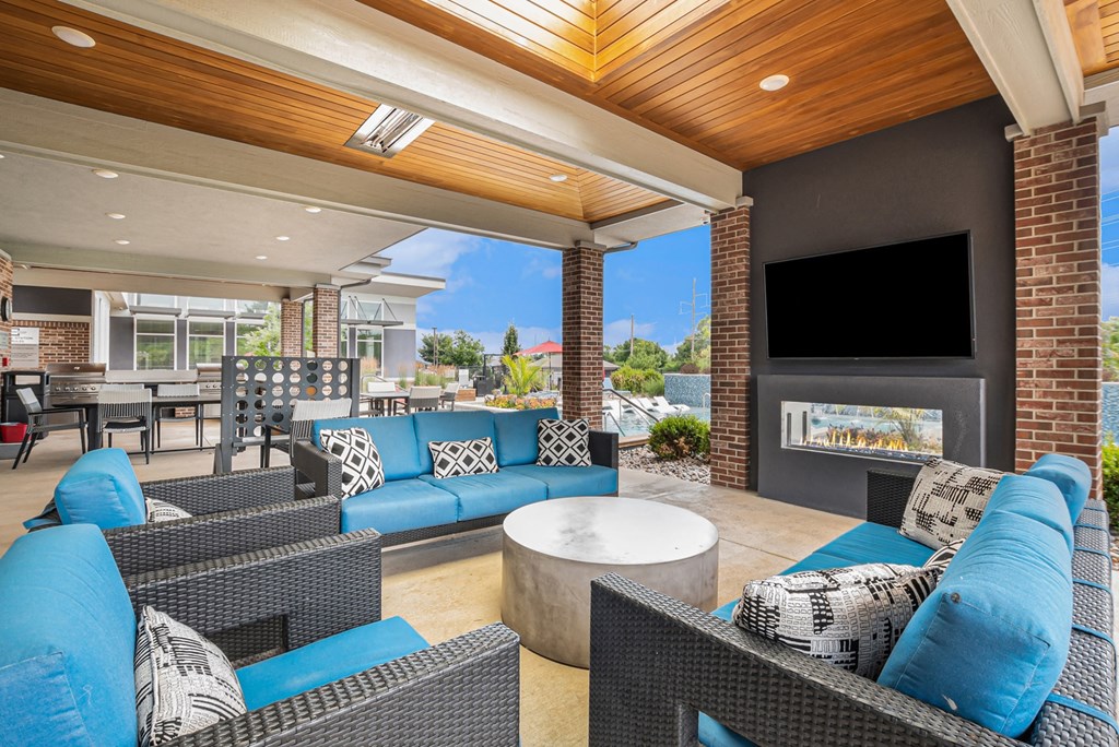 a covered patio with blue couches and chairs and a fireplace
