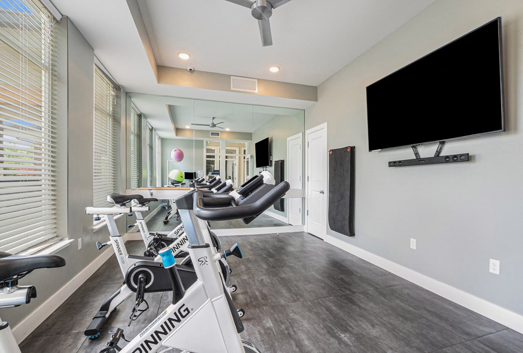 a gym with cardio equipment and a flat screen tv