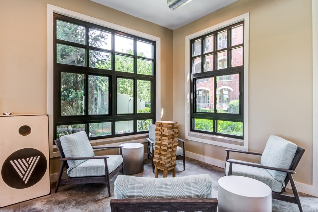 a living room with chairs and a table and large windows