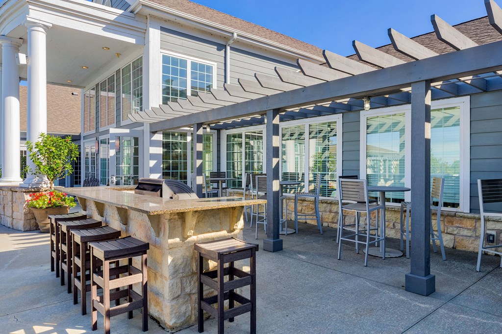 a patio with a bar and chairs in front of a building