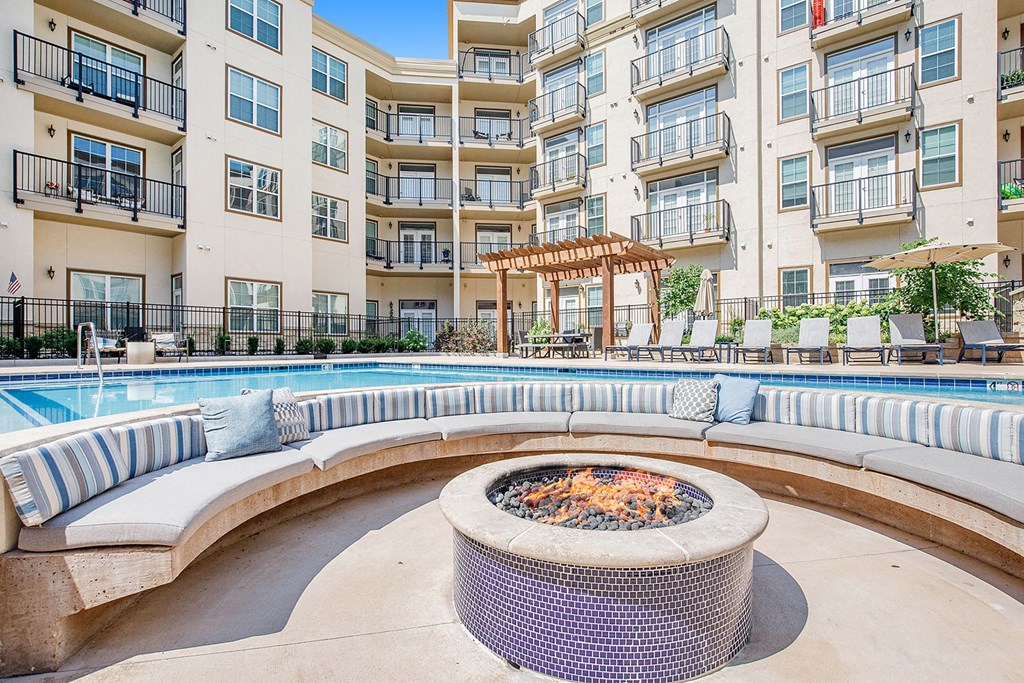 an outdoor lounge area with a fire pit in front of an apartment building