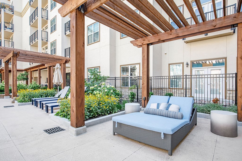 an outdoor patio with couches and chairs and an apartment building in the background