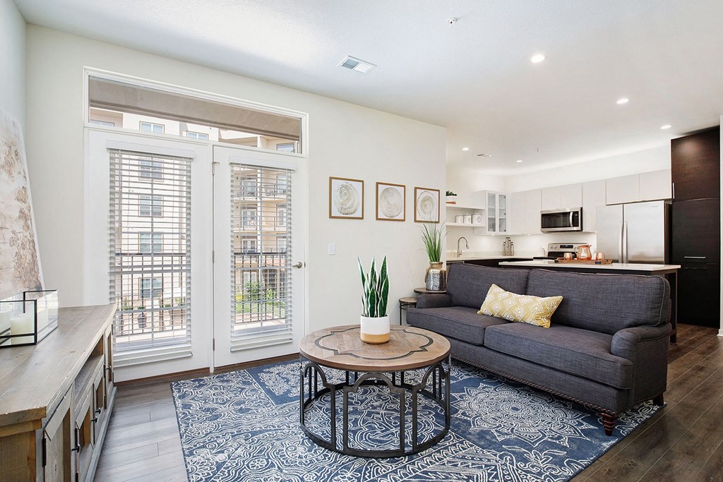 a living room with a couch and a coffee table    and a kitchen