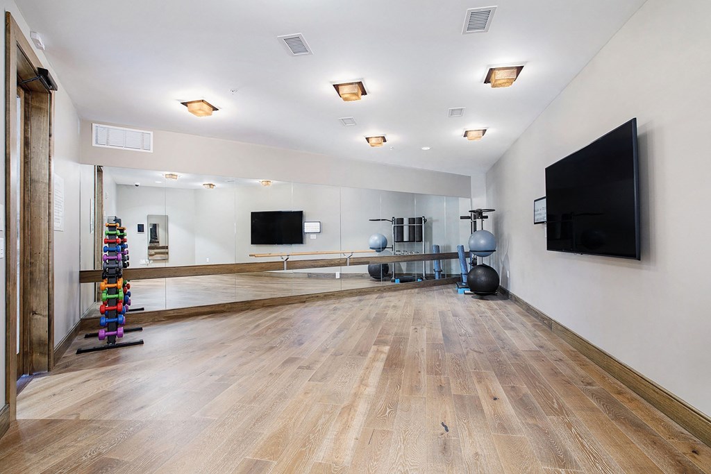 a large dance room with a tv and a mirror on the wall