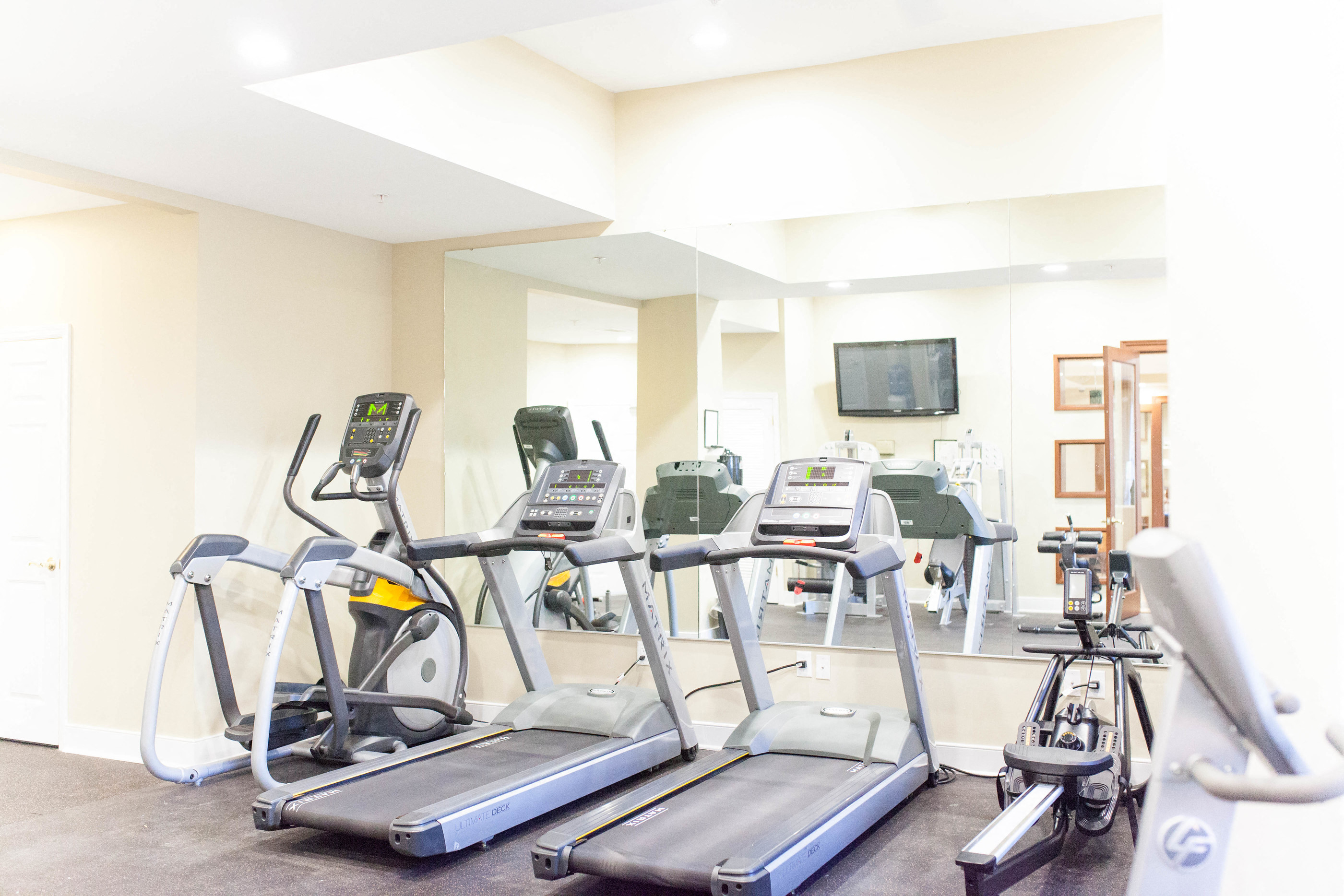 a gym with various cardio machines and a television
