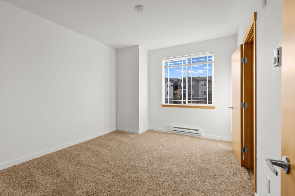 Beige Carpet In Bedroom and a window with blinds at Tustin Apartment Homes, Yelm, Washington