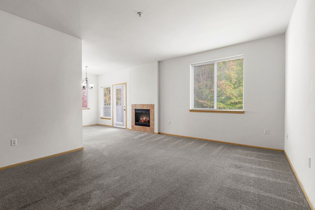 Milton Apartments - Sundance - Living Room with Open Floor Layout, Fireplace, and Plush Carpeting