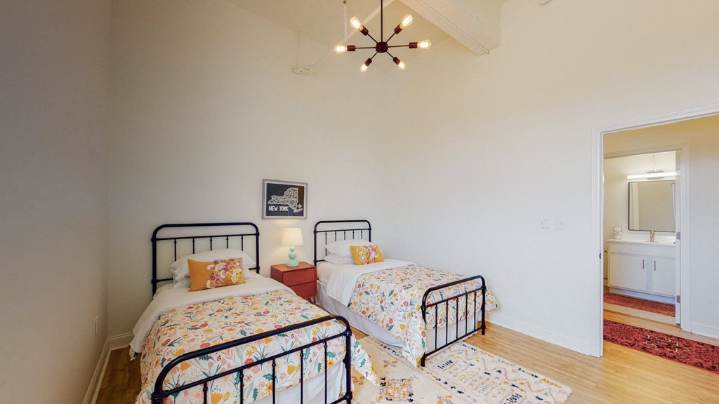 two twin beds in a bedroom with white walls and a ceiling fan