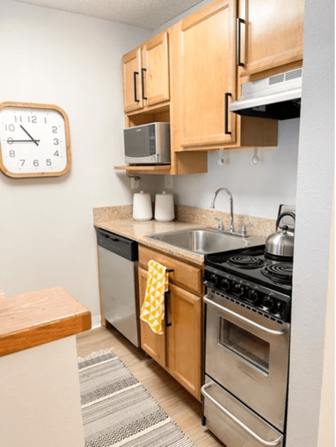 a small kitchen with stainless steel appliances and wooden cabinets