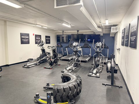 A gym with a variety of exercise equipment including treadmills, stationary bikes, and weight machines.