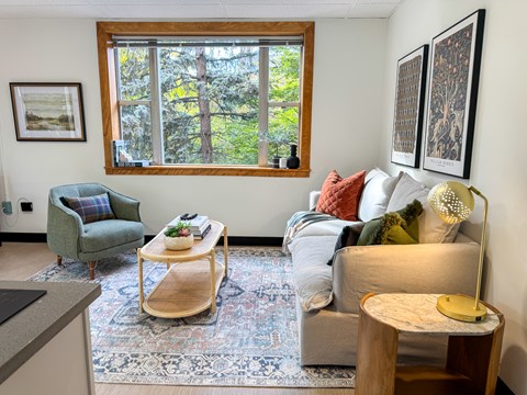 A living room with a couch, chair, and a table with a lamp.