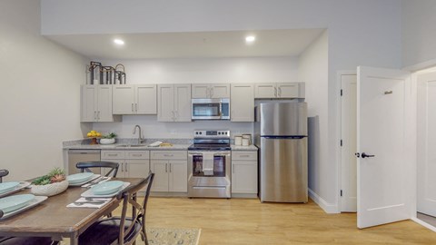 a kitchen with white cabinets and stainless steel appliances and a dining table
