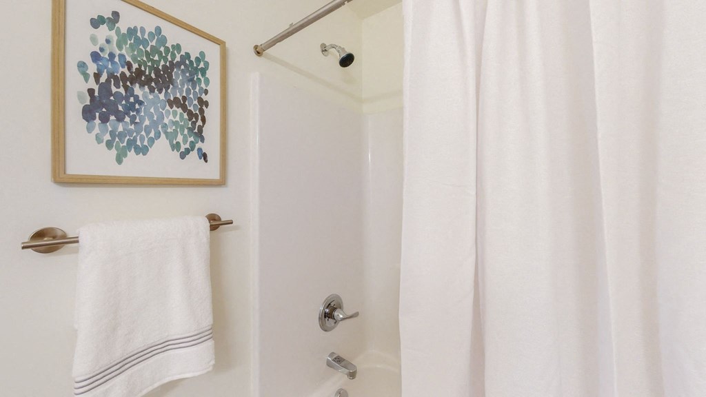 a bathroom with a white shower curtain and a white towel