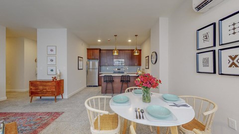 a dining room with a white table and chairs and a kitchen