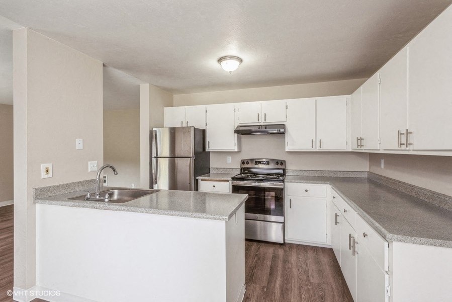 a kitchen with white cabinets and gray countertops