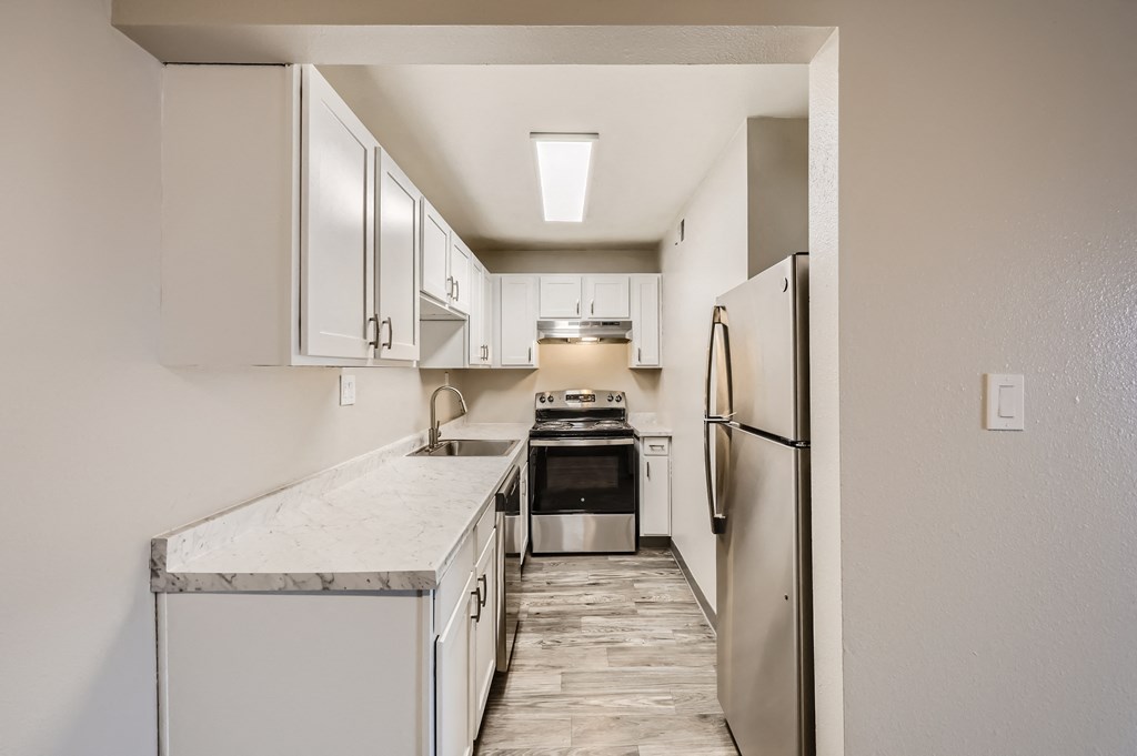 an empty kitchen with white cabinets and stainless steel appliances