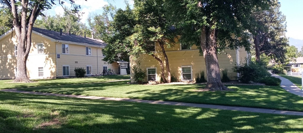 a yellow building with trees in front of it