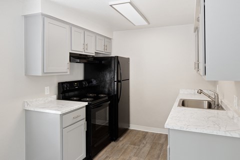 a kitchen with white cabinets and black appliances and a sink