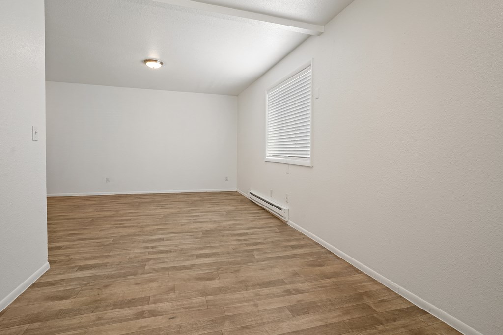 the spacious living room with wood flooring and a window