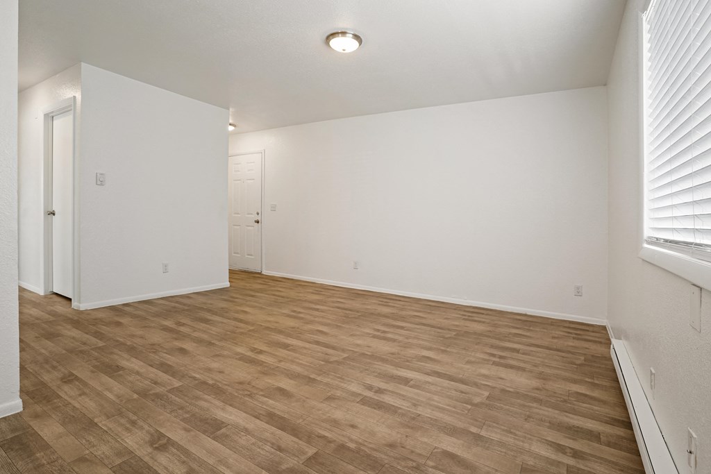 an empty living room with wood flooring and white walls