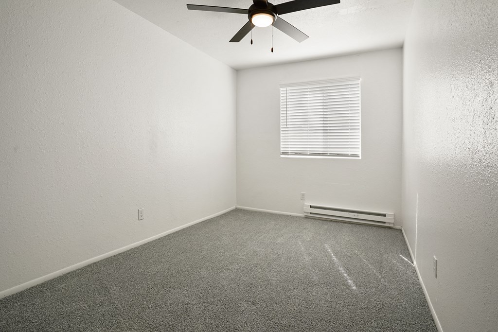 an empty room with a ceiling fan and a window