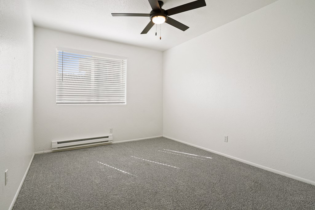 an empty room with a ceiling fan and a window
