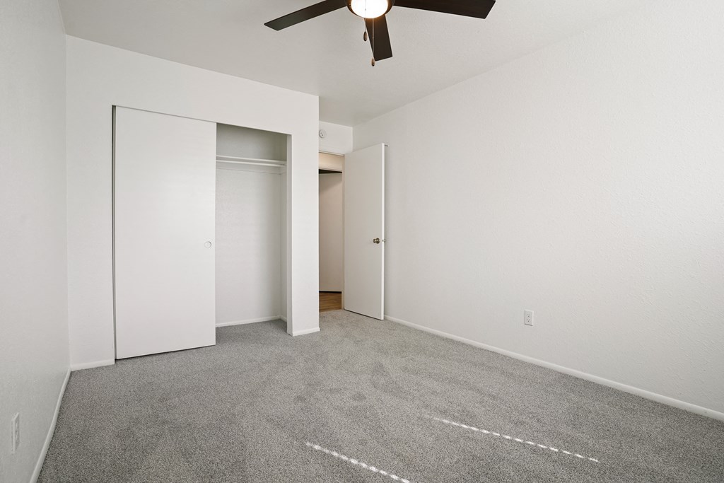 an empty room with carpet and a ceiling fan