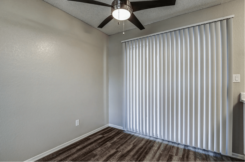 an empty living room with window blinds and a ceiling fan at Aspire Seneca, Victorville