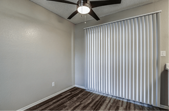 an empty living room with window blinds and a ceiling fan