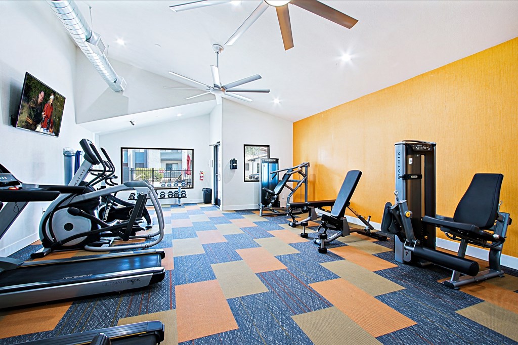 a gym with treadmills and other exercise equipment and a ceiling fan