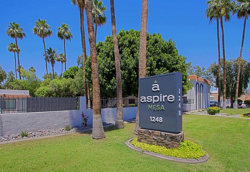 a sign for aspire west in front of a retaining wall and palm trees - Photo Gallery